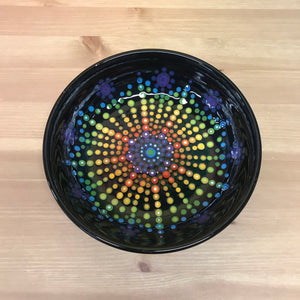 Black bowl with rainbow dots in a circular mandala pattern
